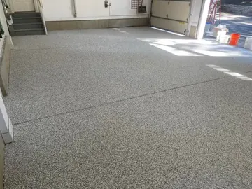 Gray flake epoxy across a three-car garage, seen from the back wall — a Greater Cincinnati job