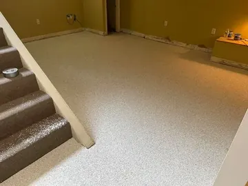 Tan flake epoxy floor at the foot of basement stairs — a Greater Cincinnati job
