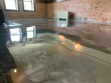 Teal and bronze metallic epoxy reflecting the windows of a brick-walled room — a Greater Cincinnati job